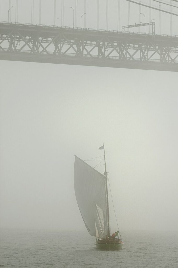 white sail boat on sea during foggy weather