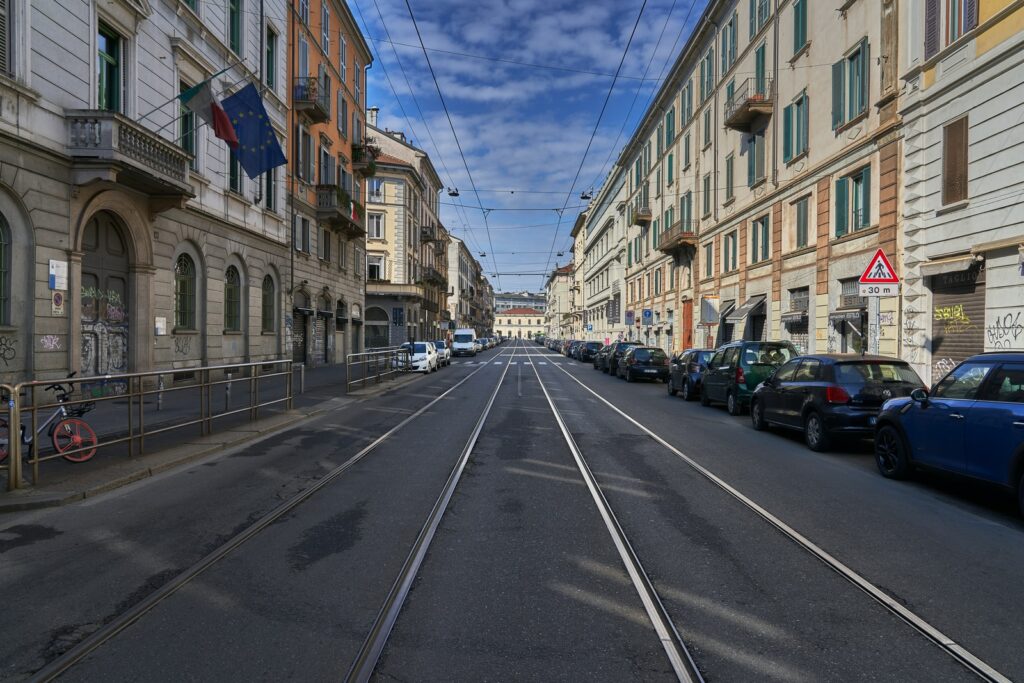 cars parked on side of the road in between buildings during daytime