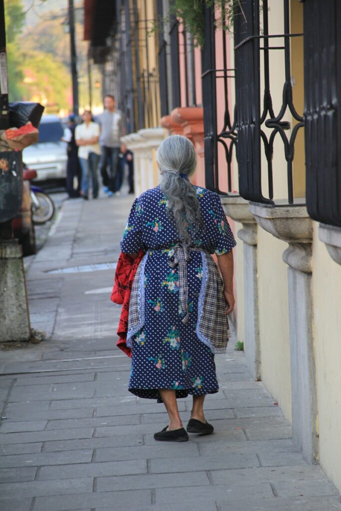 woman in red and black dress walking on sidewalk during daytime