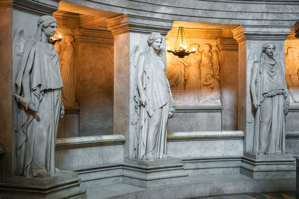 man in white robe standing beside concrete statue