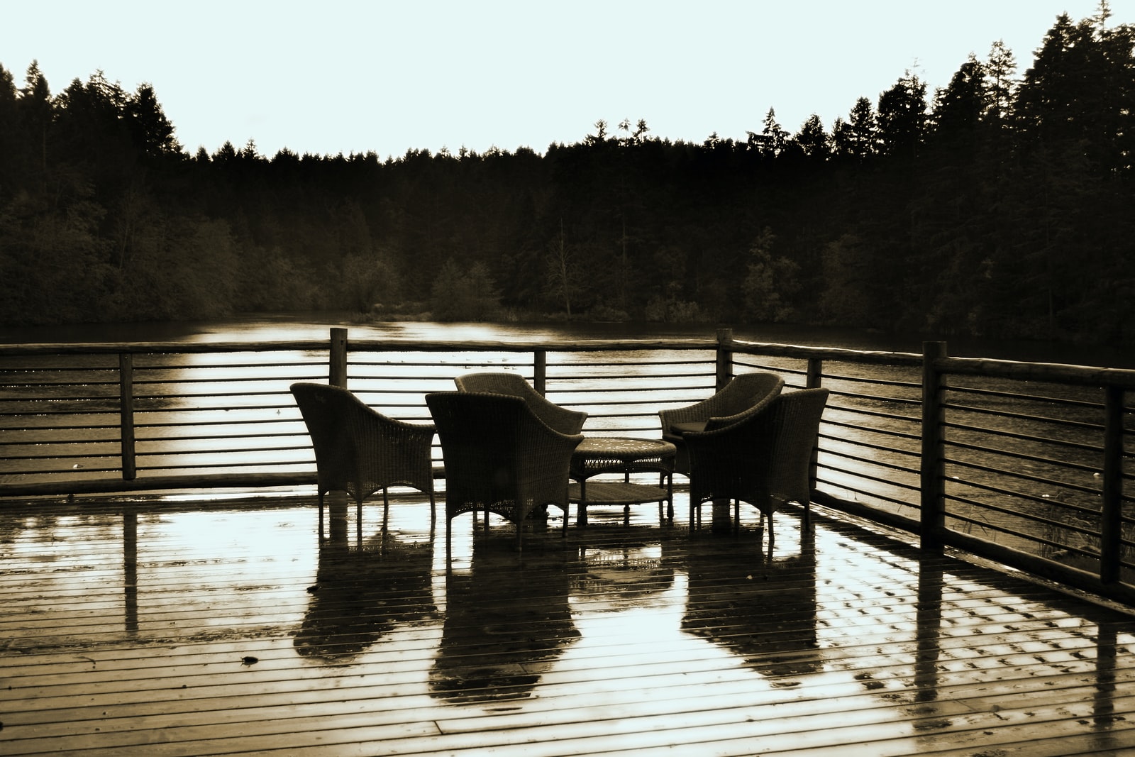 grayscale photo of two wooden chairs on wooden dock