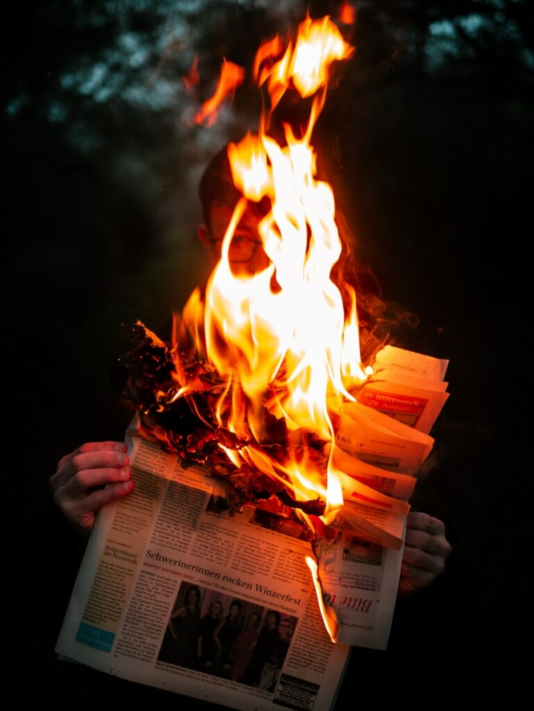 person holding burning newspaper