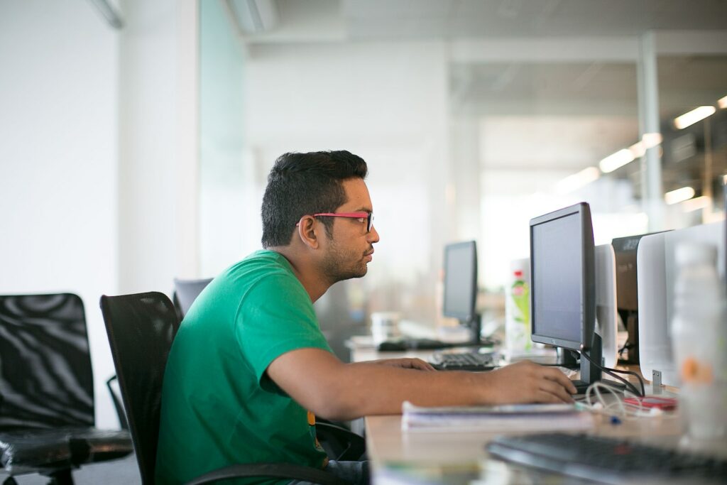 man in green crew neck t-shirt sitting on black office rolling chair