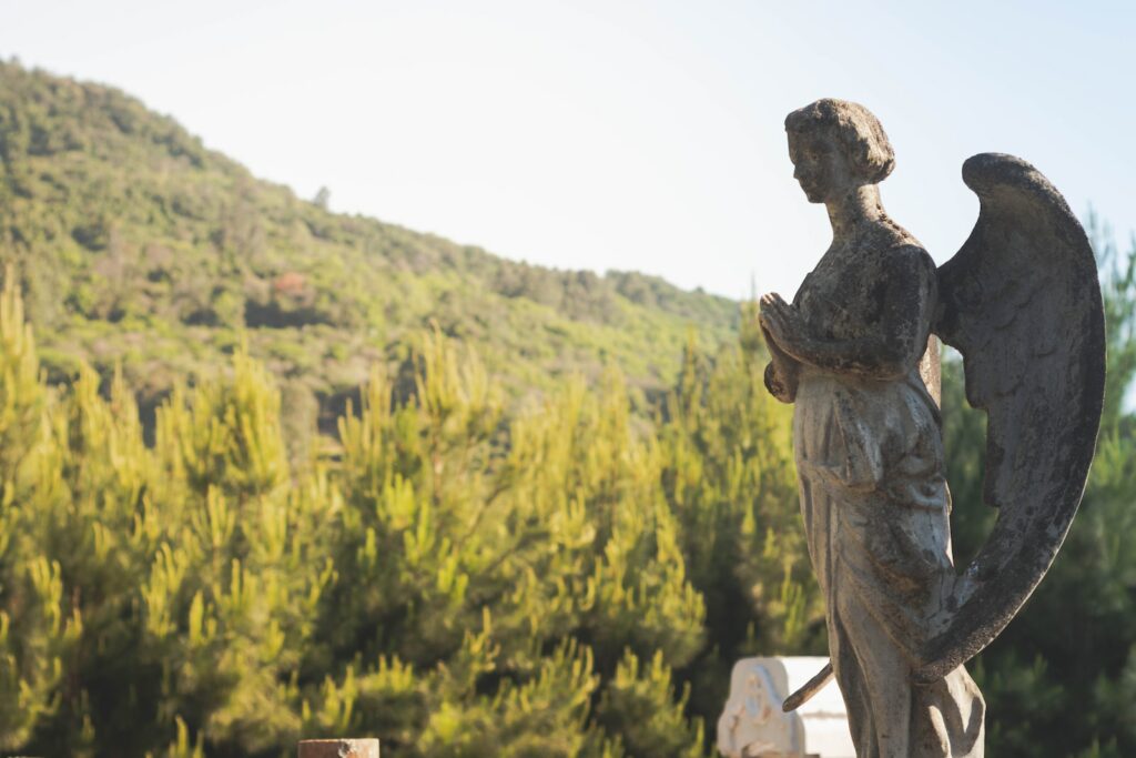 woman statue near green trees during daytime