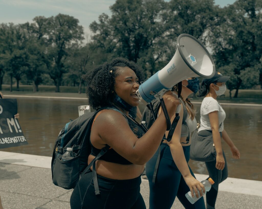 woman in black tank top and blue denim jeans holding white camera