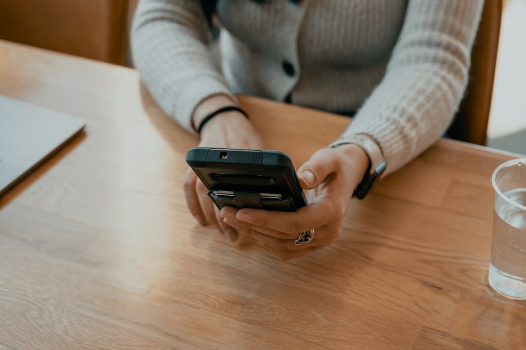 woman in white sweater holding black smartphone