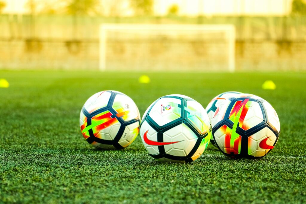 three white-and-black soccer balls on field