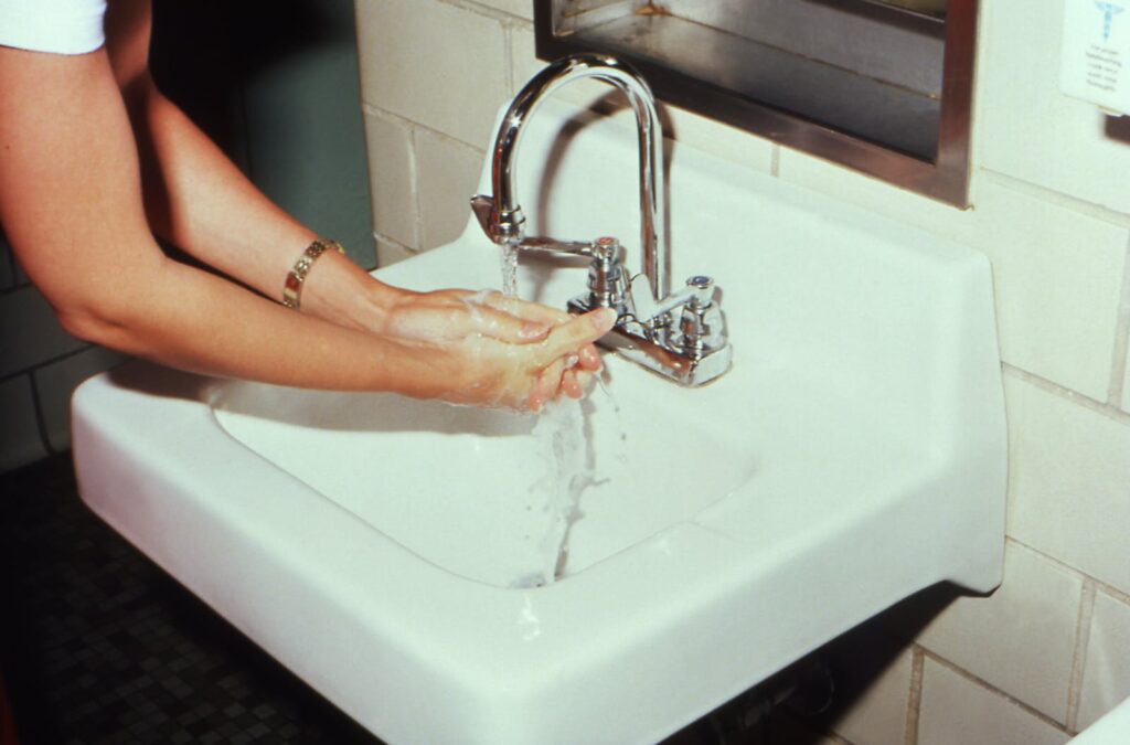 Person Washing Hands on Sink