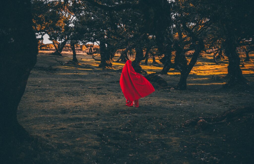 a person in a red dress sitting on the ground under a red umbrella