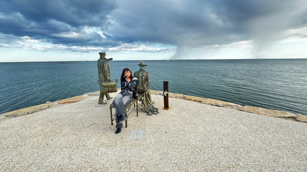 a woman sitting on a chair next to a body of water