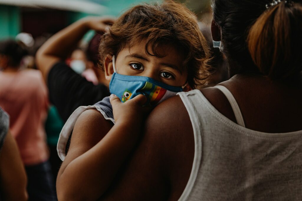 girl in white tank top holding blue and green plastic toy