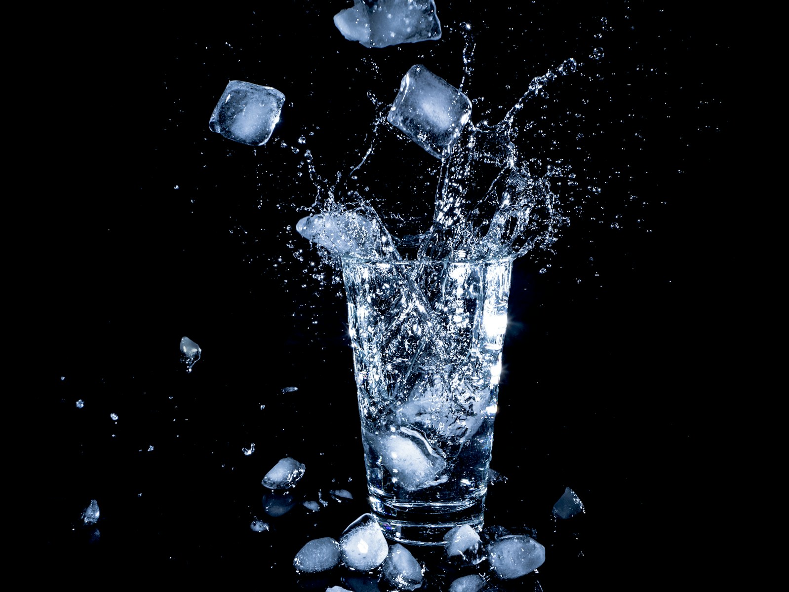 ice cubes dropped in clear drinking cup with water