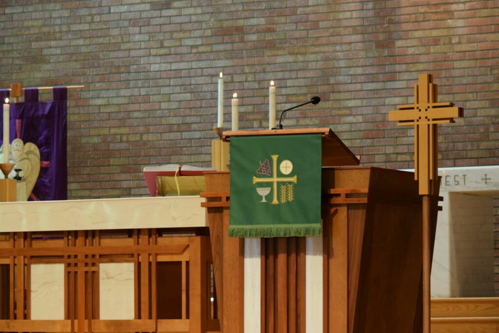 a priest standing at a podium in front of a brick wall