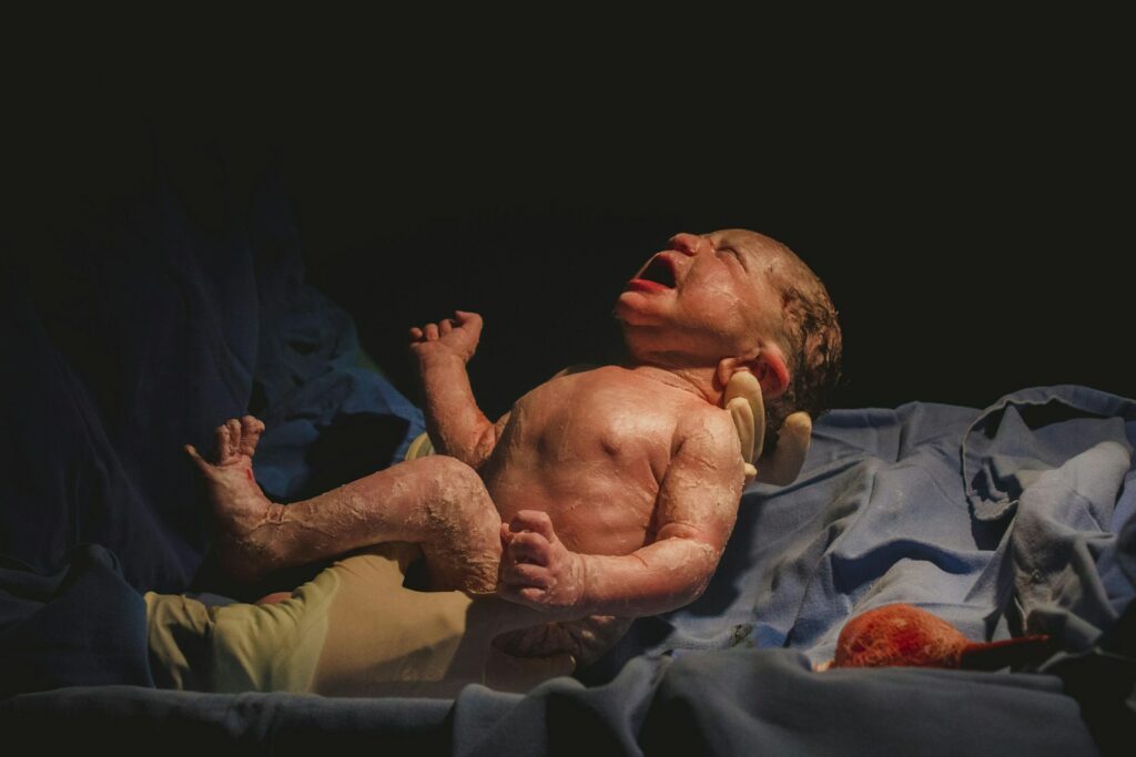 a baby laying on top of a bed next to an adult