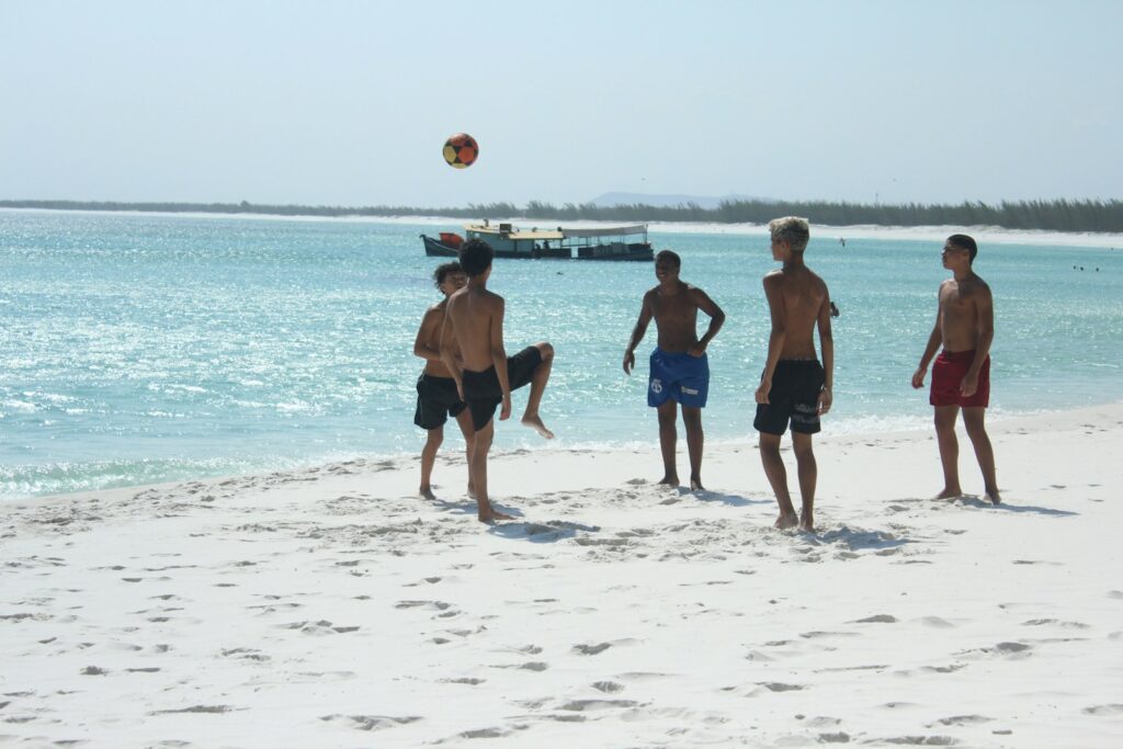 Boys playing soccer on a sunny beach