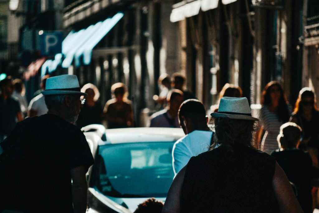 A bustling urban street filled with people walking in the sunlight.